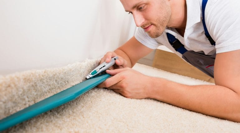close-up-of-a-young-handyman-fitting-carpet